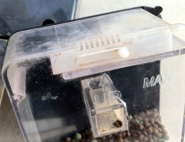 A simple 'trap door' opening, movable via line groove locking of the 'trap door', to regulate the size of the hole and therefore the amount of food dispensed. A simple 'trap door' opening, movable via line groove locking of the 'trap door', to regulate the size of the hole and therefore the amount of food dispensed.